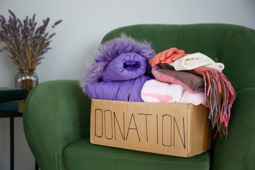 Donation box with clothes on the armchair in the living room. photo