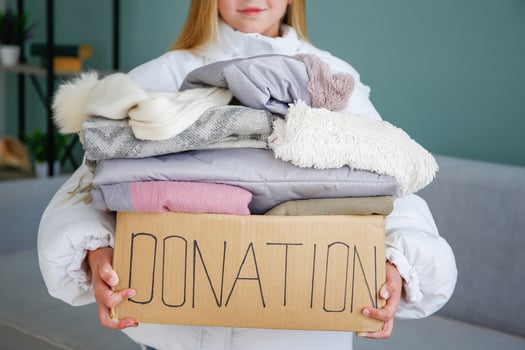 A child holds a donation box with clothes in the living room. photo