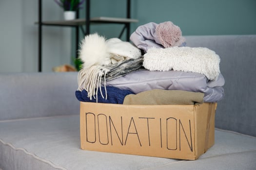 Donation box with clothes on the sofa in the living room. photo