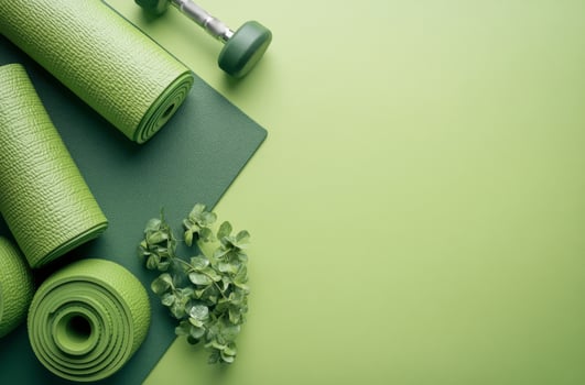 Green yoga mats and a dumbbell arranged neatly on a vibrant green background for fitness practice photo
