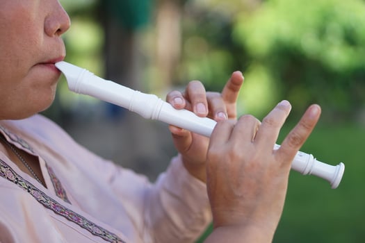 Close up woman flutist, musician is playing a recorder flute. Concept, music blowing with mouth, control with fingers on holes of flute for melody and rhythm. Mouthpiece musical instrument. photo