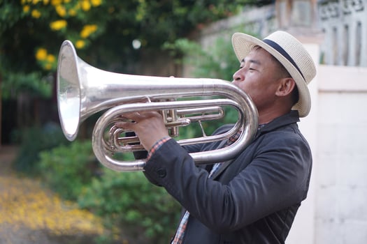 Asian man is playing the euphonium. Concept, love music, hobby, recreation activity. Relax time. Lifestyle. Music can develop mental health. Mouthpiece musical instrument. Rehearsal music. photo