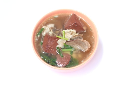Pork blood jelly soup with entrials and vegetable in light orange ceramic bowl on white background. photo