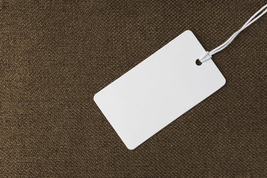 Textile background, brown coarse fabric texture with white empty clothing tag photo