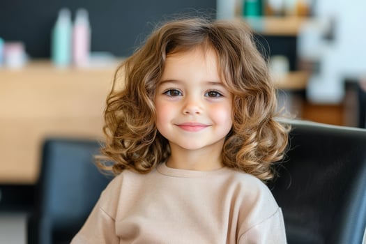 Cheerful girl sitting in salon chair during a haircut in a hairdresser photo