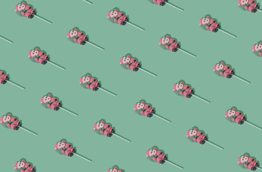 Christmas pattern made of Santa Claus lollipop on pastel green background. Minimal Christmas and New Year sweet candy concept. Creative festive pastel backdrop. Winter holiday idea. photo