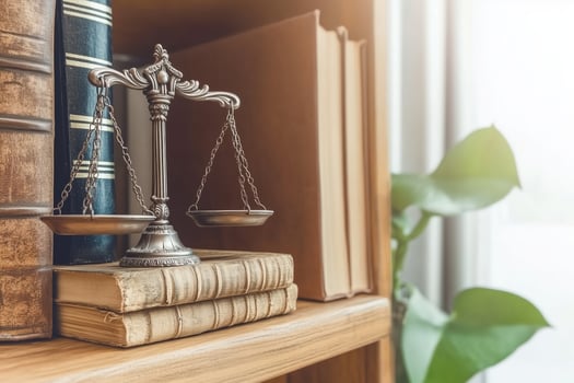 A scale of justice rests on a stack of old books, symbolizing the legal system. photo