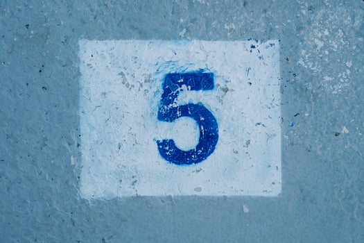 Number five with scratched paint drawn on a blue wall in a rectangle photo