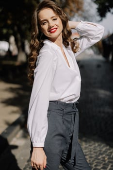 Elegant businesswoman smiling and touching hair in city street photo