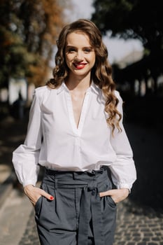 Businesswoman smiling outdoors, wearing white shirt and grey trousers photo