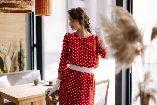Elegant woman wearing polka dot dress and gloves posing in cafe photo