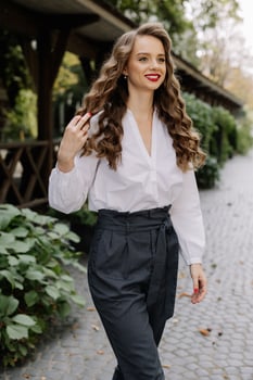 Businesswoman walking in a park touching her long brown hair photo