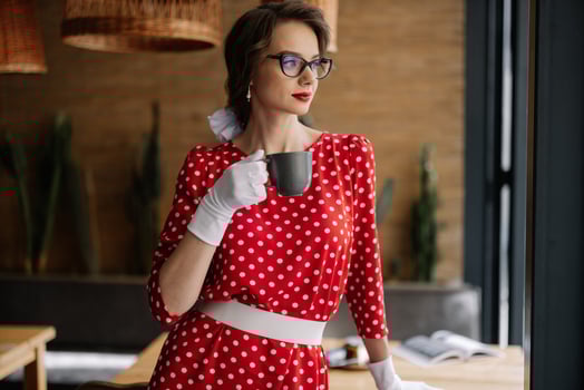 Elegant woman drinking coffee in retro polka dot dress and white gloves photo