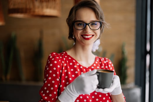Smiling waitress wearing white gloves and holding coffee cup in restaurant photo