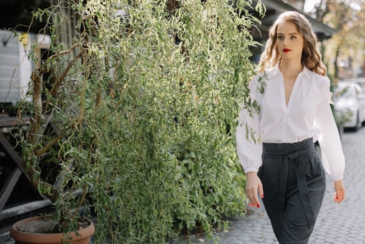 Businesswoman walking on a city sidewalk near a green plant photo