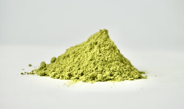 Matcha powder or finely grounded green tea isolated on horizontal white background. photo