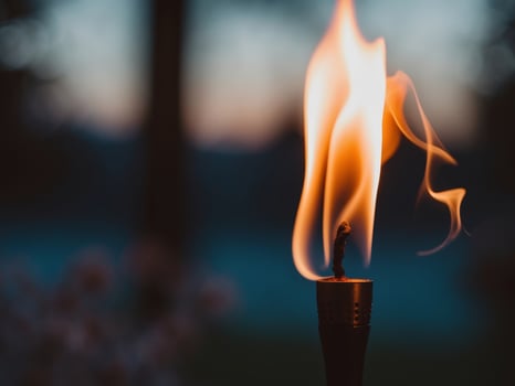 A burning candle is shown in the dark photo