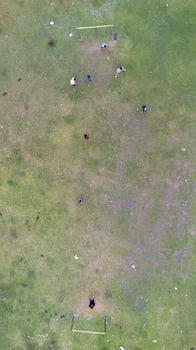 Aerial view of people playing soccer on green grass field in public park photo