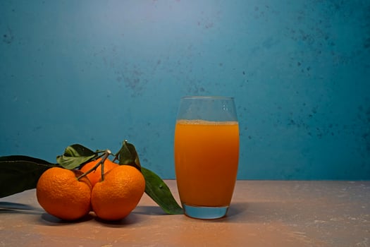 Tangerines with green leaves and a glass of juice on the table. photo