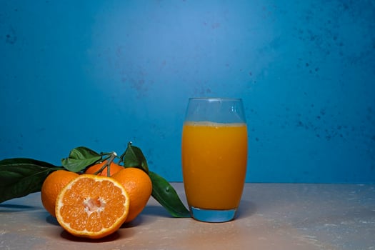 Tangerines with green leaves and a glass of juice on the table. photo