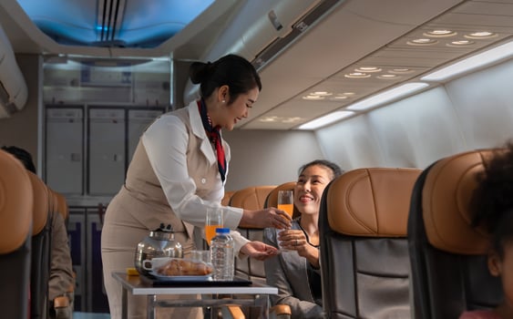 Airplane flight attendant serving orange juice to female passenger in cabin. photo