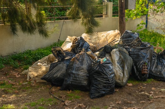 Piles of trash bags awaiting collection in a suburban outdoor setting during daylight hours photo
