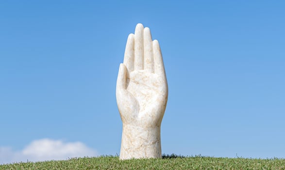 Outstretched hand statue in grassy field photo