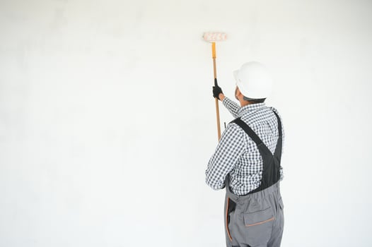 Indian Painter painting the office wall with roller paint photo