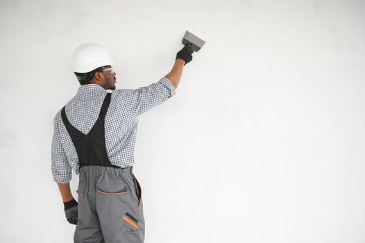 business, building, and people concept. african builder in hardhats with plastering tools indoors photo