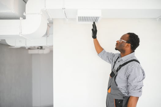 African HVAC Technician Worker Testing Newly Installed Ventilation System. Commercial Heating, Cooling and Air Ventilation Systems photo
