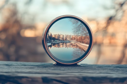 A mirror is sitting on a wooden table with a city in the background photo
