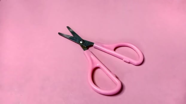 Small pink scissors on a pink background. Concept of cutting, crafting, and precision. photo