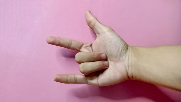 Close up of a hand forming the 'I love you' sign language against a pink background. Concept of love, affection, and communication. photo