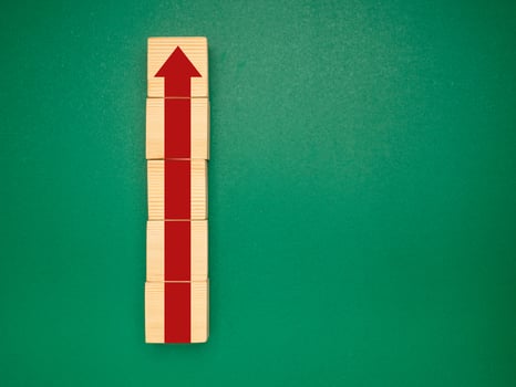 Wooden cubes with red arrows up over a green background. Business growth and strategy concept photo