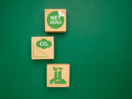 Net-zero greenhouse gas emissions target. Wooden cubes with green icons over a green background photo