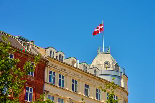 National Danish flag waving on roof of historical building on sunny day photo