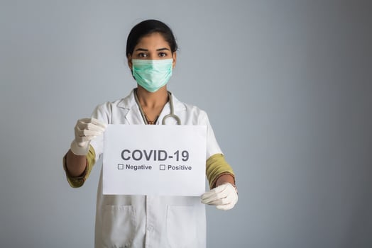 A young woman doctor in a medical mask holding a board of the epidemic of Coronavirus, Covid-19 photo