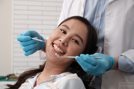 Close-up shot of beautiful Asian female face, white teeth, and cheerful face in dentist's hand, dental treatment with tooth whitening and cleaning in doctor hospital clinic, oral hygiene healthcare. photo