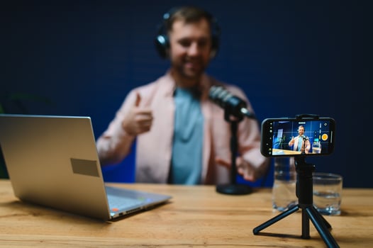 Man podcaster influencer blogger smiling while broadcasting his live audio podcast in studio using headphones. Male radio host making podcast or interview photo