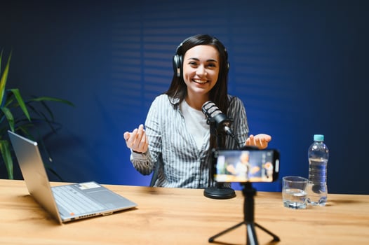 Positive female vlogger recording a on camera sitting at desk photo