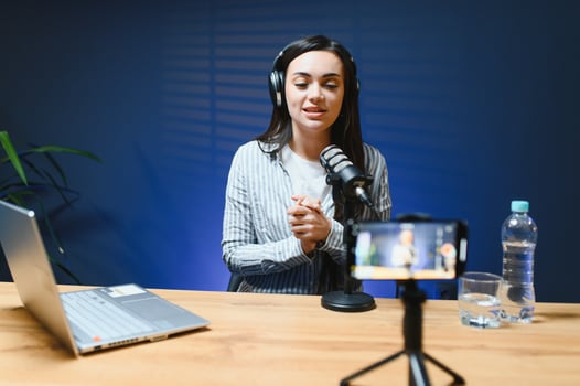 Female vlogger influencer speaking looking at camera, young woman blogger greets fans and talks looking into smartphone, participating in online conference photo