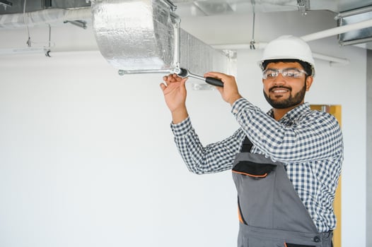 An Indian worker inspects the ventilation system in an office building photo