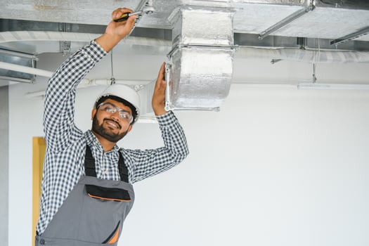 An Indian worker inspects the ventilation system in an office building photo