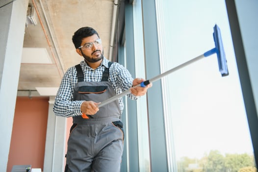 Male professional cleaning service worker cleans the windows and shop windows of a store with special equipment photo