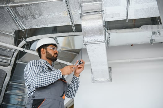 An Indian worker inspects the ventilation system in an office building photo