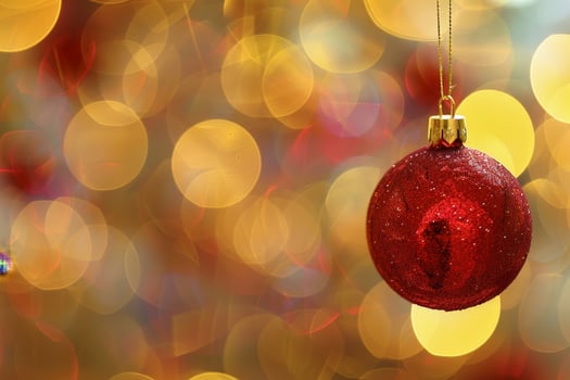 Sparkling red christmas ornament hanging on blurred golden lights background photo