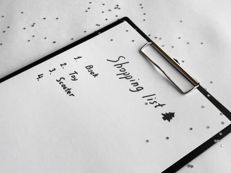 Holiday shopping list on festive clipboard with star confetti and seasonal decorations photo