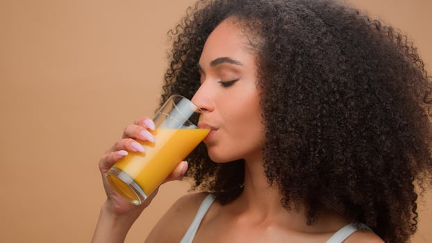 Beautiful happy healthy African American woman ethnic girl female model with curly hair drinking fresh orange juice vitamin drink diet detox organic vegetarian health care smiling in studio background photo