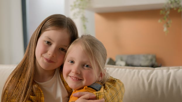Portrait happy cute little caucasian girls children sisters kids friends smiling look at each other hugging embracing cuddle looking camera family love care affection relationship embrace hug indoors photo