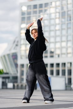 Young woman performing dance moves outdoors in urban setting during daytime photo